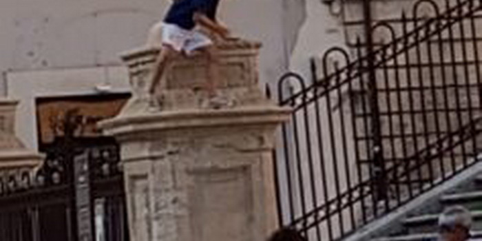 Ragazzino si arrampica sul basamento di una delle statue di San Pietro a Modica